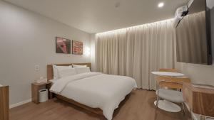 a hotel room with a white bed and a desk at Maison de Centum Busan in Busan