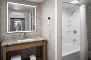 a bathroom with a sink and a tub and a mirror at The Harrison Hotel Downtown Hollywood FL, an Ascend Collection Hotel in Hollywood