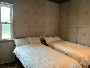 two twin beds in a room with a window at リベルテ Work & Vacation Villa Nosoko in Ibaruma