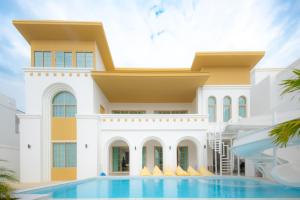 a house with a swimming pool in front of it at Brown Empire Pool Villa Pattaya in Nong Prue