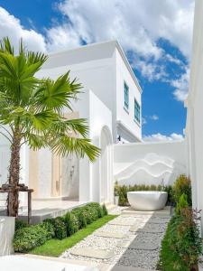 a white house with a palm tree in the yard at Brown Empire Pool Villa Pattaya in Nong Prue +47 photos