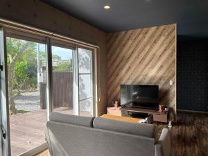 a living room with a couch and a flat screen tv at リベルテ Work & Vacation Villa Nosoko in Ibaruma