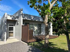 a small white house with a tree in front of it at リベルテ Work & Vacation Villa Nosoko in Ibaruma