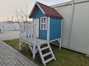 a blue and white house with a ladder and a chair at Autentic Adorabil Apartment in Albeştii Pămînteni