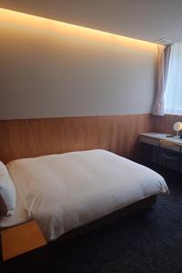 a bedroom with a white bed with a wooden headboard at ライベストイン奄美アネックス in Koniya +24 photos