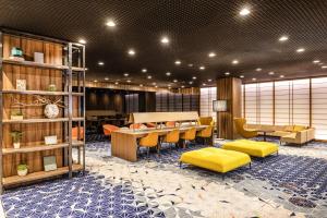 a lobby with a table and yellow chairs and a room at Shinjuku Prince Hotel in Tokyo