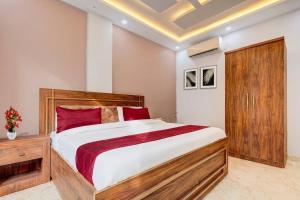 a bedroom with a large bed with red pillows at Super Hotel Pari Chowk Formerly The Divine KRC in Greater Noida