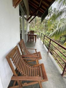 two wooden benches sitting on the porch of a house at Coconut Villa in Bentota