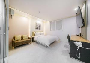 a bedroom with a bed and a couch and a tv at Ilsan Hotel K in Goyang