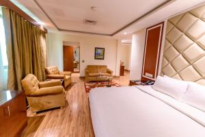 a hotel room with a bed and two chairs at Hotel One Faisalabad in Faisalabad