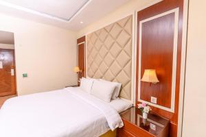 a bedroom with a white bed and a wooden headboard at Hotel One Faisalabad in Faisalabad
