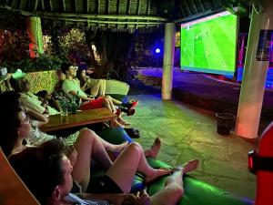 a group of people watching a soccer game on a tv at Stay Social Diani - Backpackers & Social Hub in Diani Beach