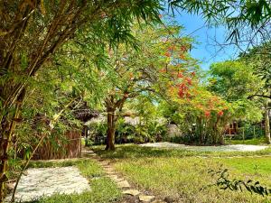a garden with trees and grass and a fence at Stay Social Diani - Backpackers & Social Hub in Diani Beach