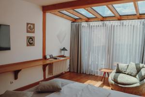 a bedroom with a bed and a chair and a window at Hotel Gut Hühnerhof in Gründau