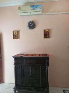 a black cabinet with a clock on a wall at Our Place Silk Island in Silk Island