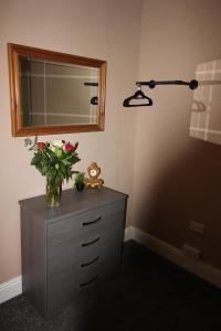 a dresser with a mirror and a vase of flowers on it at Cornerhouse Apartments 3 Sleeps 7 in Llandudno +34 photos