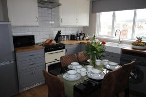 a kitchen with a table with dishes on it at Cornerhouse Apartments 4 Sleeps 5 in Llandudno
