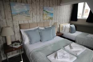 a bedroom with two beds with blue and white pillows at Cornerhouse Apartments 4 Sleeps 5 in Llandudno