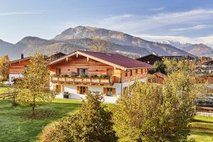 a large wooden house with mountains in the background at Ferienwohnung Dosbach in Reit im Winkl