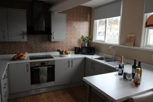 a kitchen with white cabinets and a table with wine bottles at Cornerhouse Apartments 5 Sleeps 5 in Llandudno