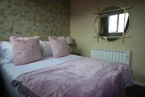a bedroom with a bed with pink pillows and a mirror at Cornerhouse Apartments 5 Sleeps 5 in Llandudno +8 photos