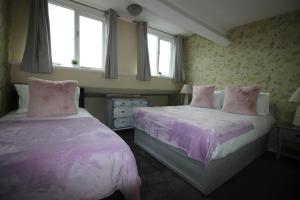 a bedroom with two beds with pink sheets and flowers at Cornerhouse Apartments 5 Sleeps 5 in Llandudno