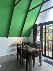 a dining room with a green ceiling and a table and chairs at Mias Home in Sunggal