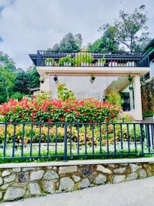a fence in front of a house with flowers at Clover Cottage in Nuwara Eliya