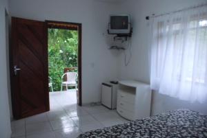a bedroom with a bed and a television and a door at Pousada Chale Cana Brava in Guaramiranga