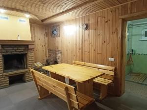 a wooden table and bench in a room with a fireplace at Гостьовий будинок з банею in Bohuslav