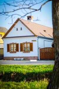 a white house with brown windows and a fence at Antik Porta-Hangulatos parasztház kerttel,borospincével és infraszaunával in Szakony