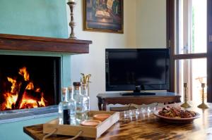 a living room with a fireplace and a table with a television at Centaur Suites & Maisonettes in Miléai