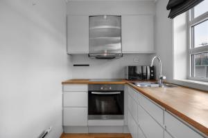 a white kitchen with a sink and a microwave at Northstay - Skansegata Apartments, Apartment B l One-Bedroom in Tromsø +6 photos