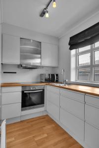 a kitchen with white cabinets and a stove top oven at Northstay - Skansegata Apartments, Apartment B l One-Bedroom in Tromsø