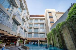 a hotel with a swimming pool in front of a building at Bedrock Hotel Kuta in Kuta