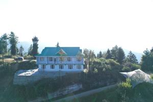 a large white house with a green roof at Forest rest house Tannu Jubbar - Ecotourism in Kanethi +9 photos