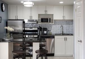 una cocina con armarios blancos y electrodomésticos de acero inoxidable en Mountain Side Studio at The Blue Mountains, en Blue Mountains