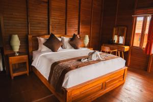 a bedroom with a large bed with wooden walls at Munduk Seming Cottages in Munduk