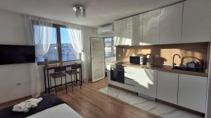 a kitchen with white cabinets and a table and a counter at Hotel Cheese in Shumen
