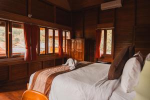 a bed in a room with wooden walls and windows at Munduk Seming Cottages in Munduk +35 photos