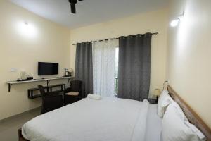 a bedroom with a bed and a desk and a television at Bougain Villa in Madikeri