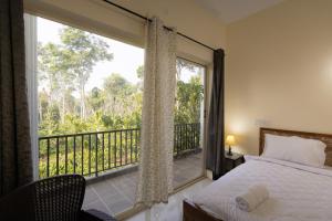 a bedroom with a bed and a balcony with a window at Bougain Villa in Madikeri