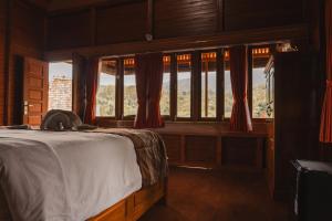 a bedroom with a bed and a large window at Munduk Seming Cottages in Munduk