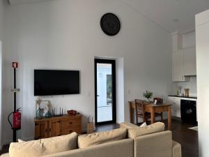 a living room with a couch and a tv on a wall at Herdade do Lameiro - Sea & Mountain Retreat in Ribeira Grande