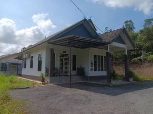 a white house with an umbrella in front of it at Sri Biah Homestay in Kuala Berang