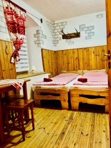 two beds in a room with wooden floors and a table at pension U Jiřího in Ludvíkov