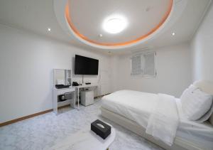 a white bedroom with a bed and a flat screen tv at Hasen Dangjin Tourist Hotel in Dangjin
