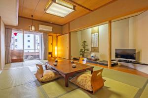 a living room with a table and a television at Osaka Ryokan Kuramoto in Osaka