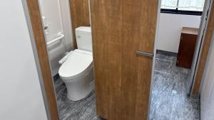 a bathroom with a toilet and a wooden door at 楽校うらしり in Uwajima