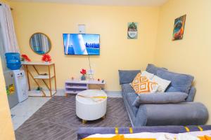 a living room with a blue couch and a tv at A&M Luxury bnbs in Nairobi +5 photos